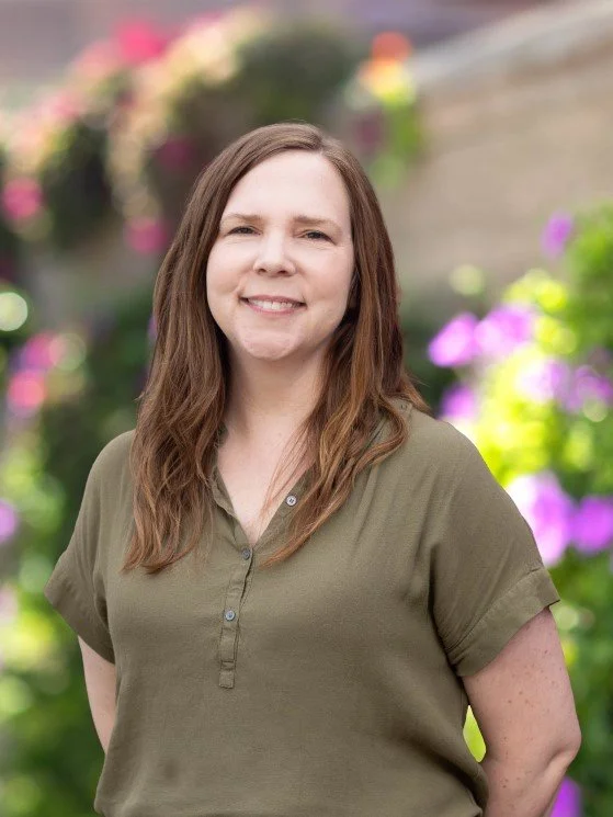 Jackie Williams-Reade, Licensed Marriage and Family Therapist, smiling in an olive green shirt in front of an outdoor floral backdrop