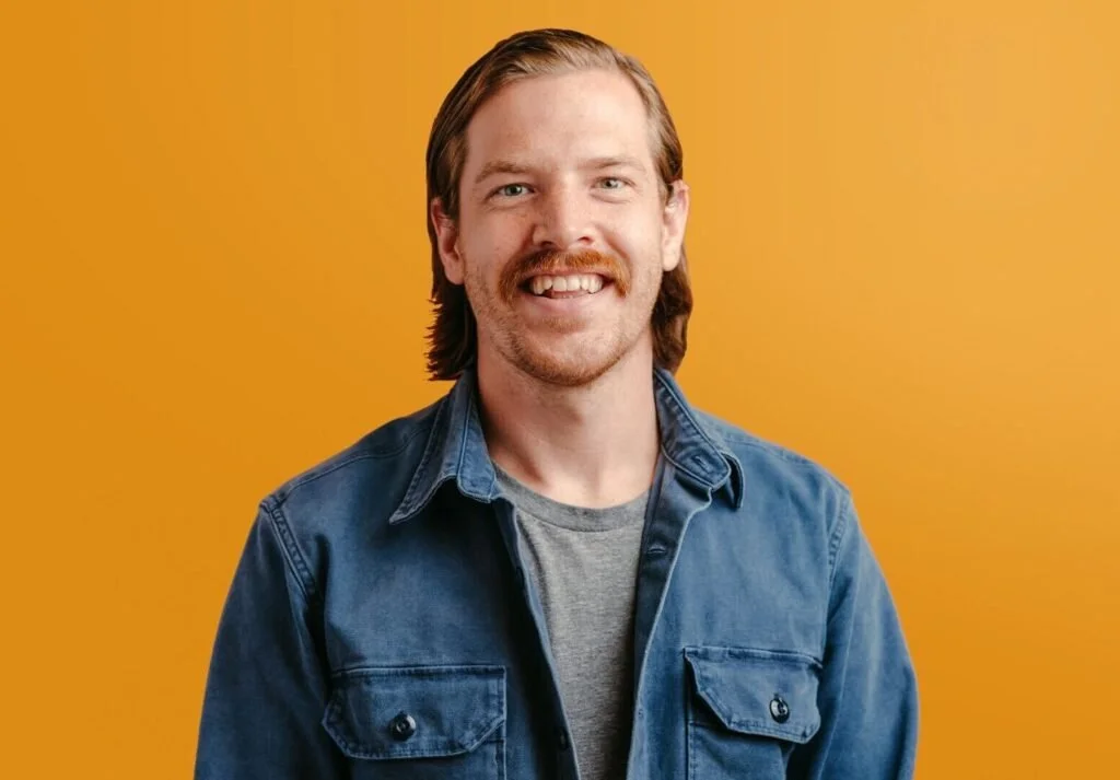Jared Walker, Dollar For founder, smiling wearing a blue button-down shirt over a grey t-shirt