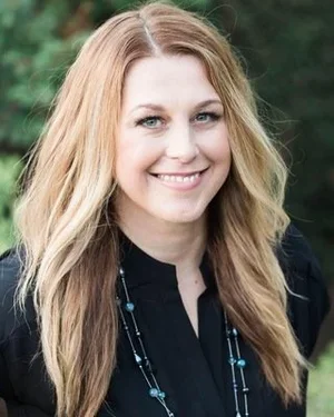 Kara Cruz, Licensed Marriage & Family Therapist, smiling wearing a black top and a long beaded necklace