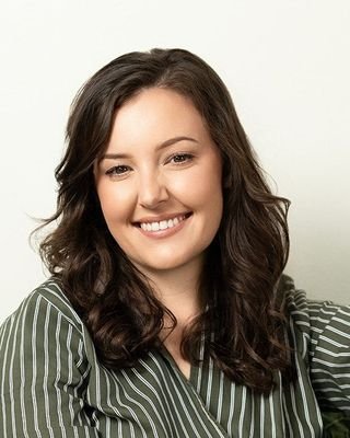Victoria Rodriguez, Licensed Professional Counselor, smiling in a green and white striped shirt against a solid light backdrop