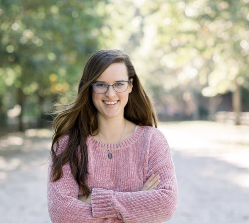 Destiny Davis, LPC CRC, smiling in a pink sweater standing outdoors with crossed arms