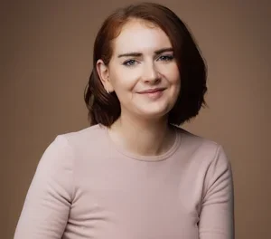 Emma Tynan, an Irish psychotherapist, smiling wearing a light pink long-sleeved top