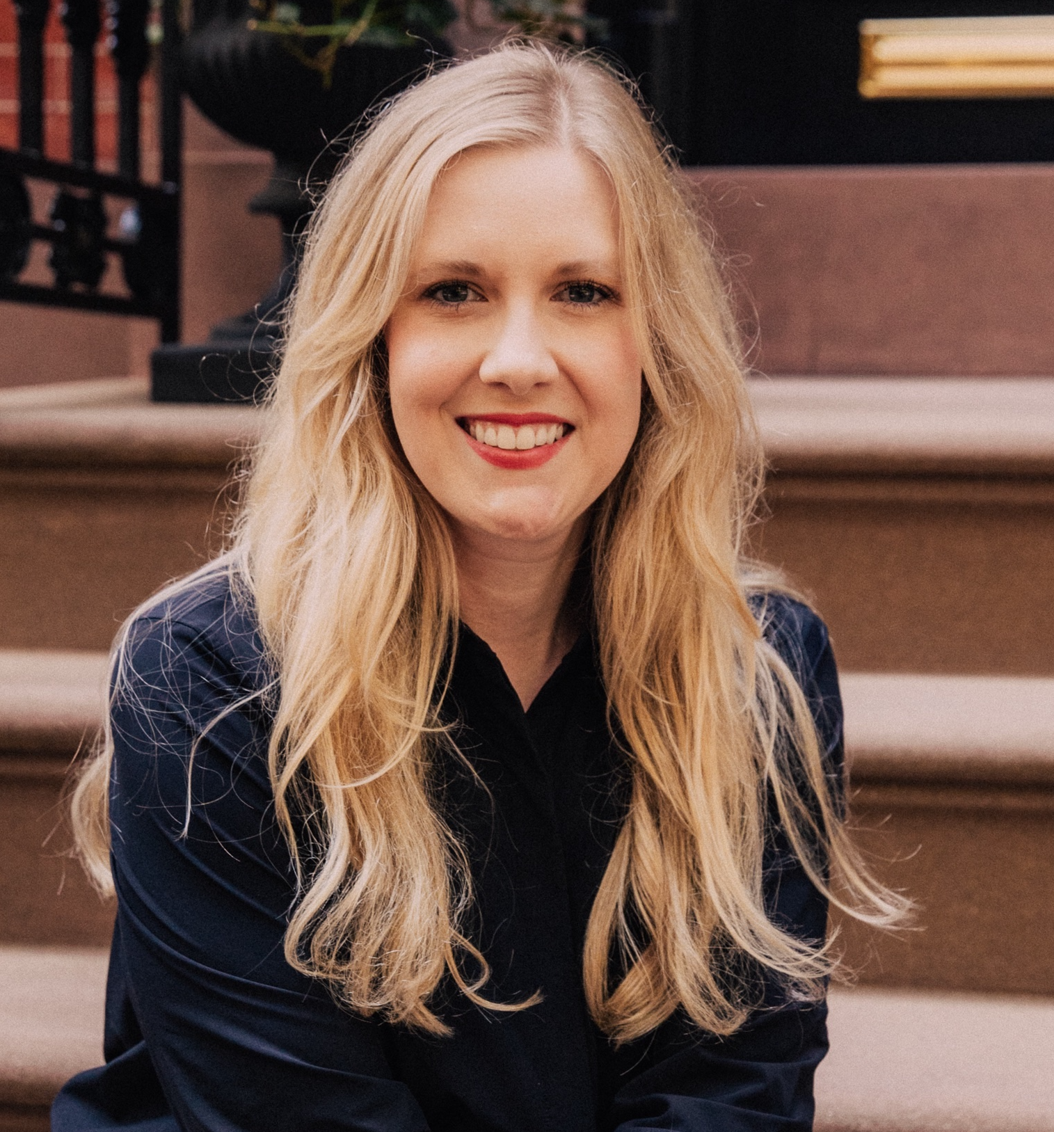 Kelsey Bates, Licensed Professional Counselor, smiling in a dark shirt seated on outdoor steps