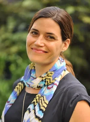 Kate Zera Kray, Licensed Clinical Social Worker, smiling wearing a colorful patterned scarf against a blurred green background