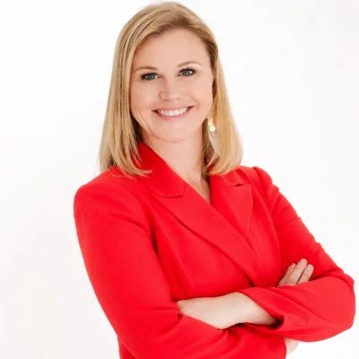 Lucy Dunning, Licensed Professional Counselor and private practice owner, smiling in a bright red blazer with arms crossed against a white backdrop.