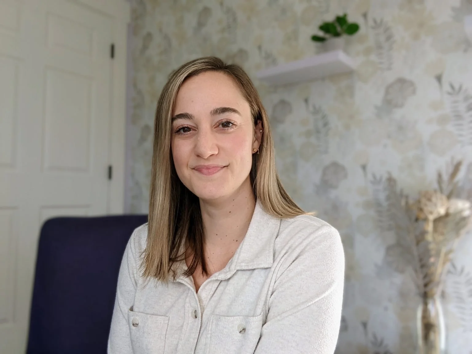 Lexi Gross, Licensed Clinical Mental Health Counselo, smiling in a light cream button-down top sitting indoors