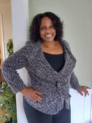 Rhonda Thorington, Licensed Professional Counselor, smiling wearing a grey knit cardigan jacket over a black top standing in a doorway with her hand on her hip