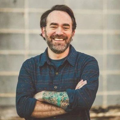 Tyler Orr, Licensed Professional Counselor, smiling in a blue button-down shirt with arms crossed