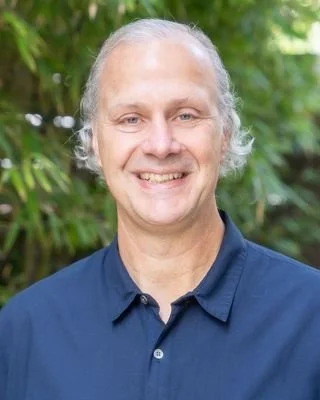 Matthew Morse, Licensed Mental Health Counselor, smiling in a navy blue polo shirt outdoors in front of green leaves