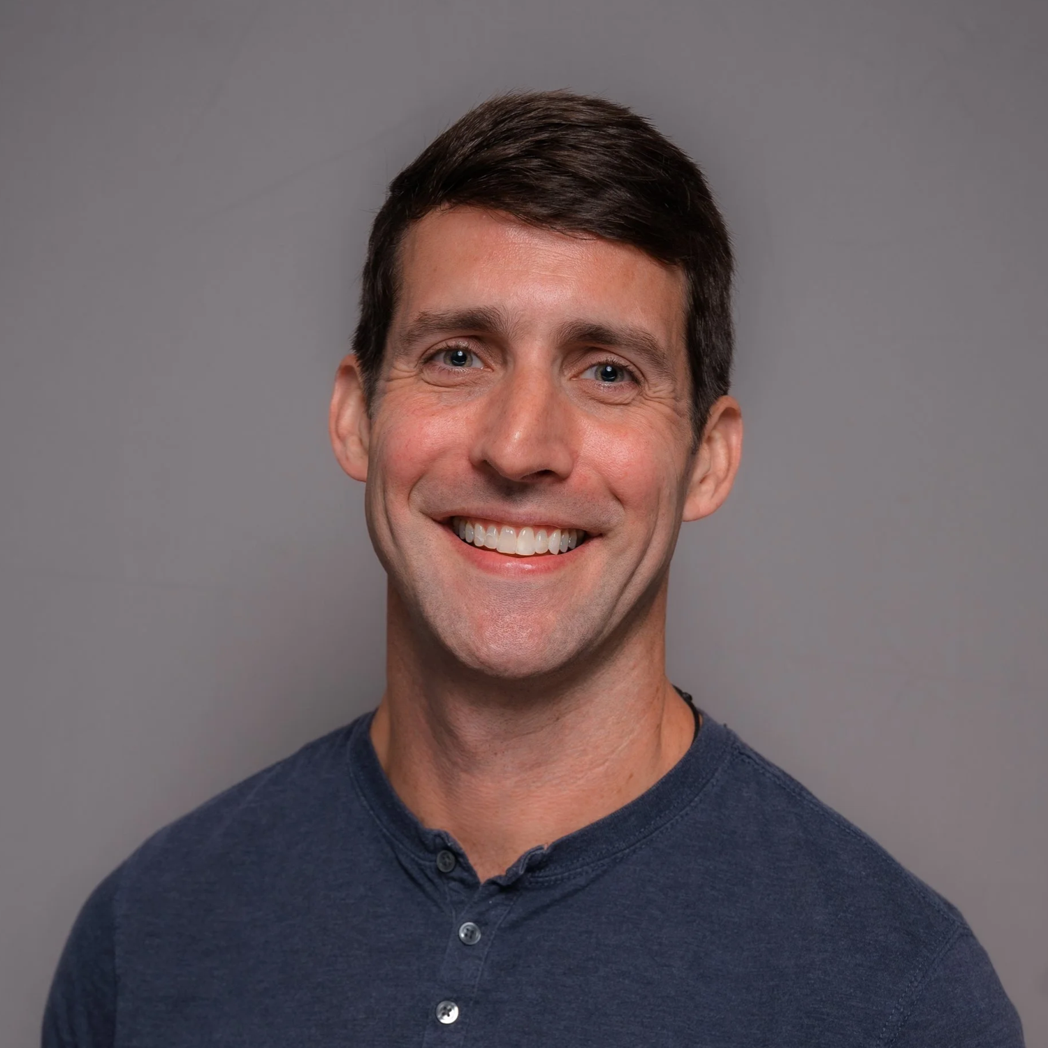 Jason Therrien, Doctor of Physical Therapy, smiling in a blue shirt in front of a gray background.