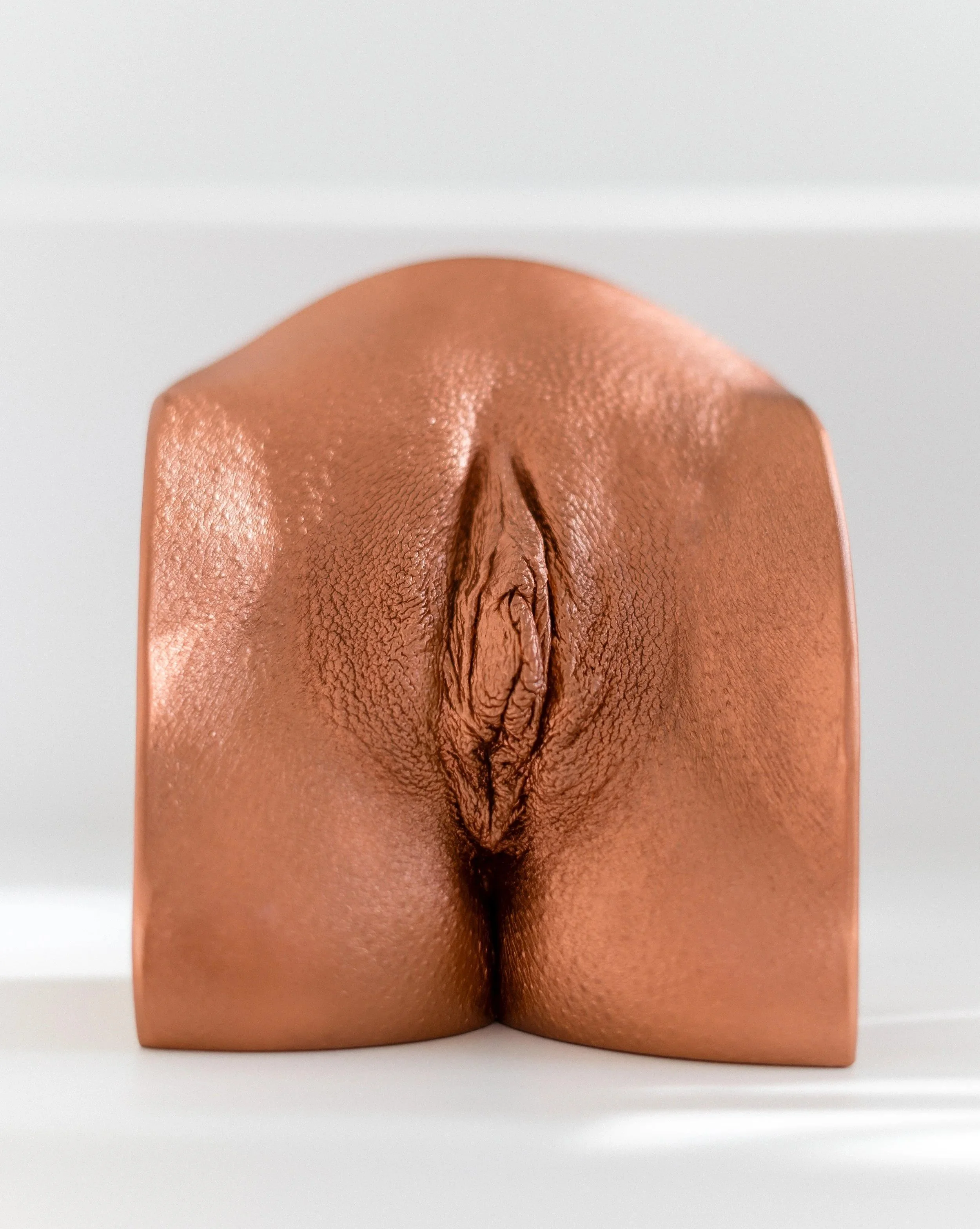 Eine bronzefarbene Vulva-Skulptur.
