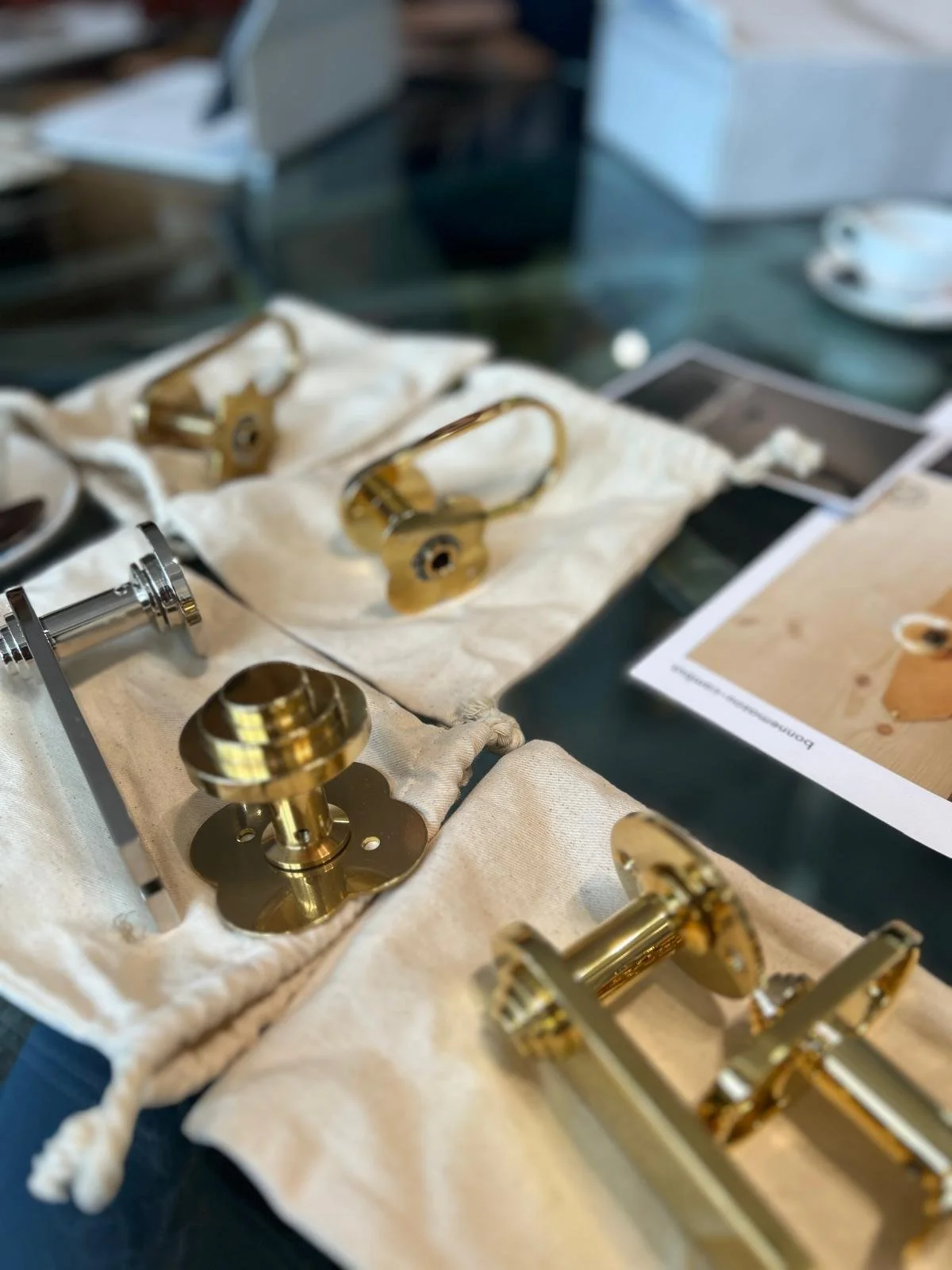 Pièces métalliques dorées et argentées, probablement pour une horlogerie ou un assemblage mécanique, posées sur un tissu blanc avec une fiche d'instructions ou un manuel à côté.
