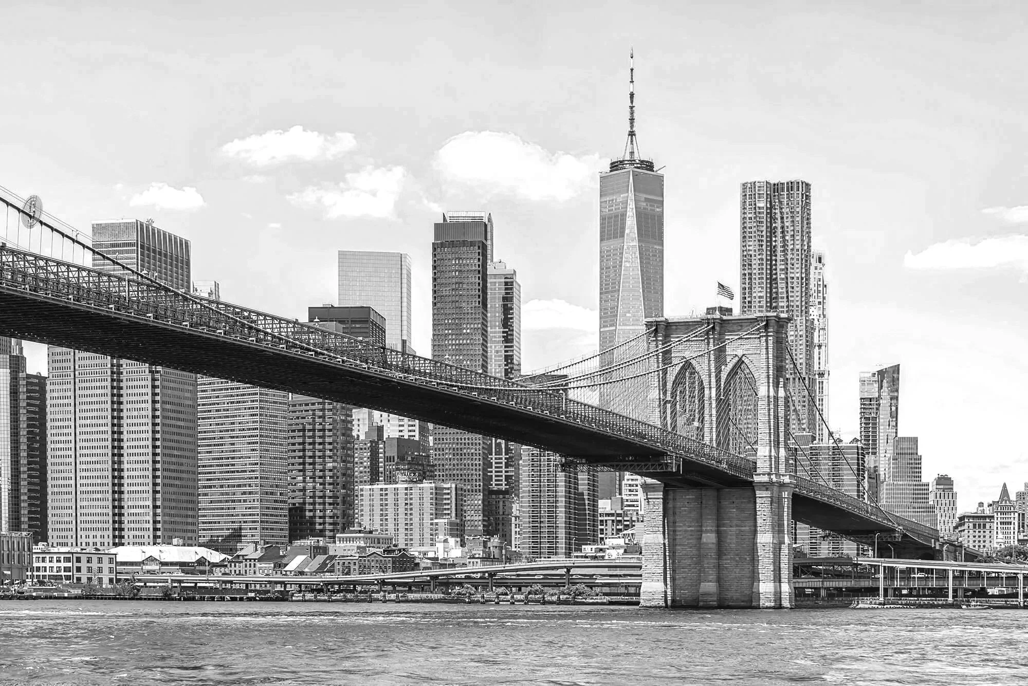 Vue en noir et blanc du pont de Brooklyn avec la skyline de Manhattan en arrière-plan, comprenant la tour One World Trade Center.