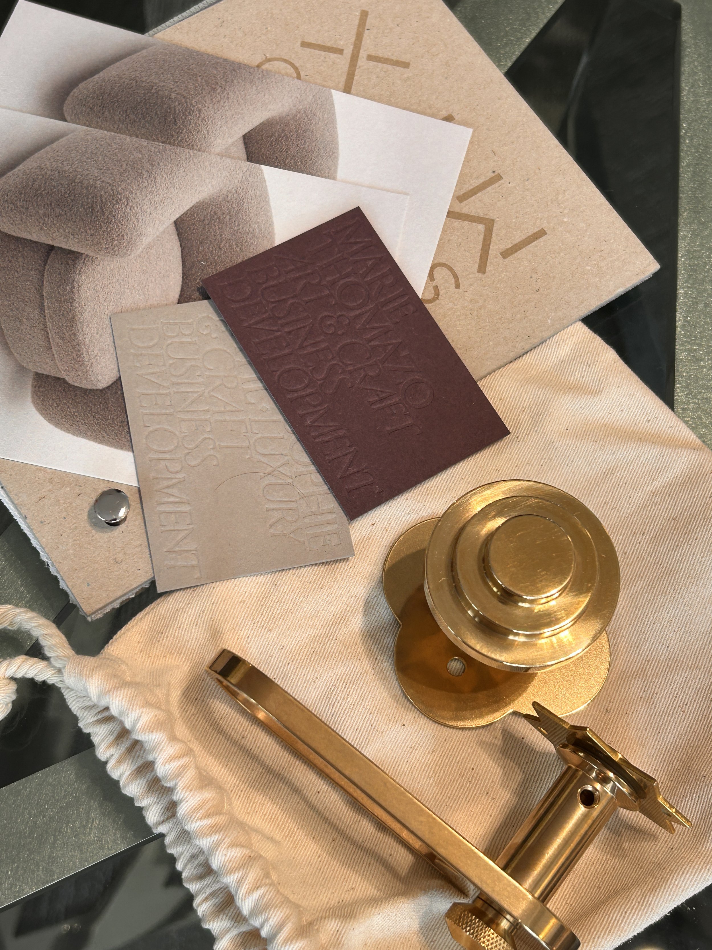 Une sélection d'articles de mode, y compris un insert en cuir rouge, un échantillon de tissu beige, des cartes de couleurs, une pièce de décoration dorée et une clé.