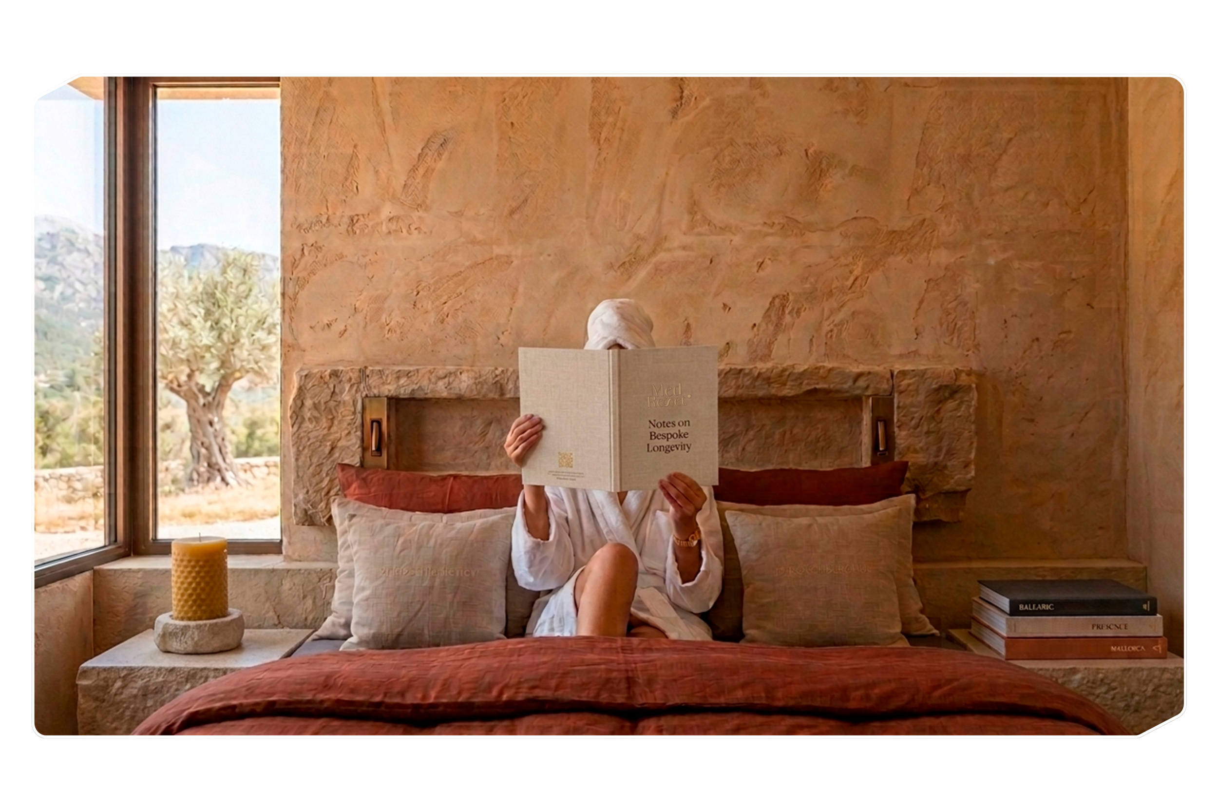 Person sitting on a bed reading a book titled 'Notes on Bespoke Longevity' in a room with a large window and a view of trees outside.