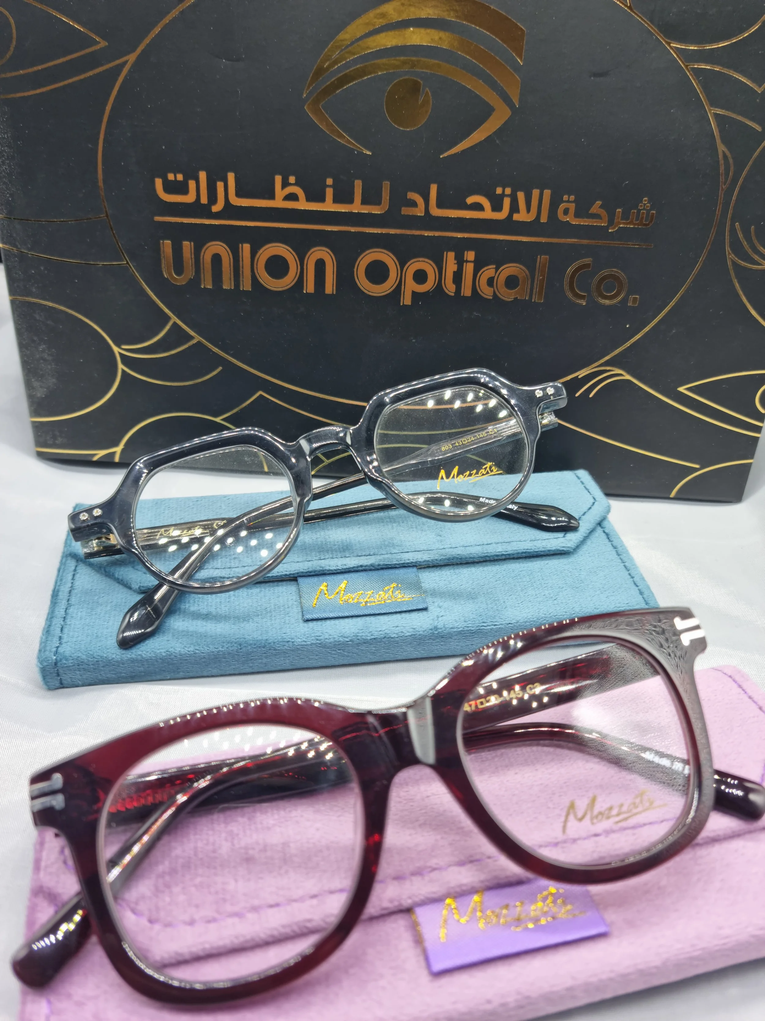 Two pairs of eyeglasses with colorful cases and a black box with gold lettering and eye logo, displaying the brand union optical co.