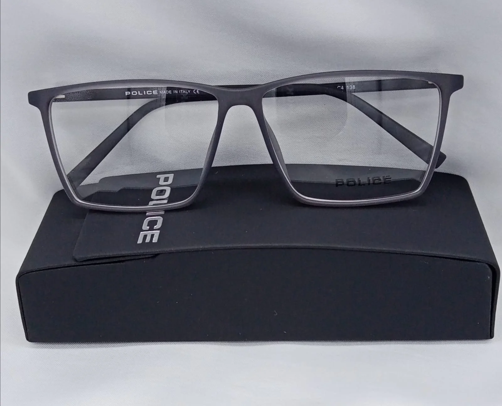 A pair of black Police brand eyeglasses resting on a black case with the Police logo.