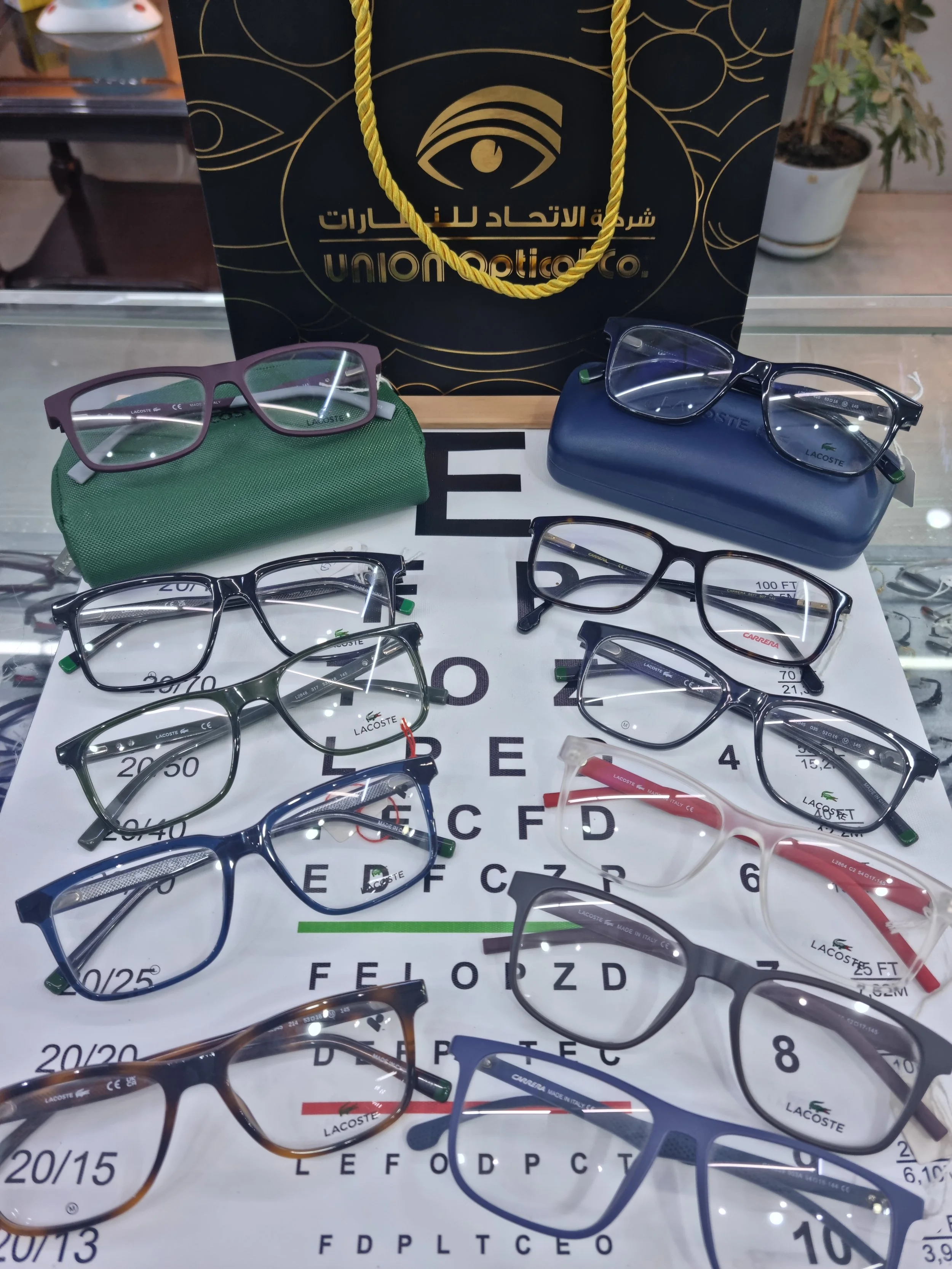 Display of multiple pairs of eyeglasses on an eye chart with a Union Optical shopping bag in the background.