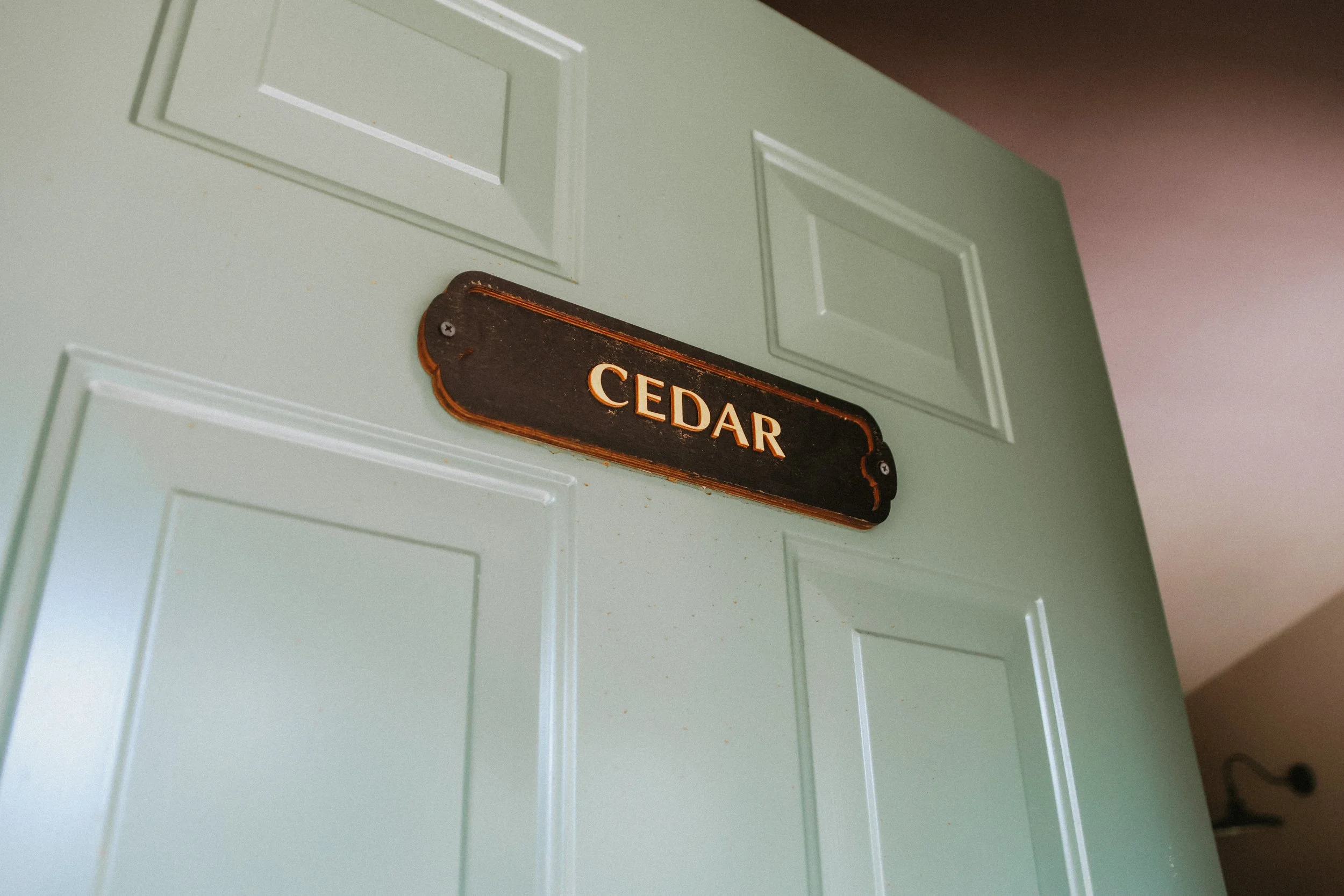 A door with a brass plaque that reads 'CEDAR' in a room with beige walls.