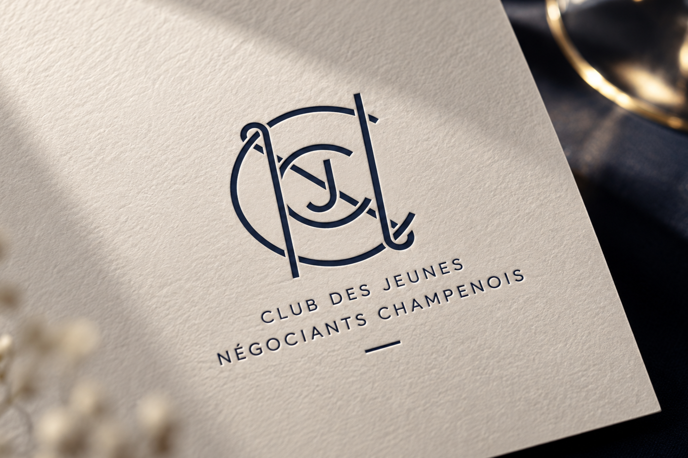 Logo du Club des Jeunes Négociants Champenois sur une carte en papier crème.