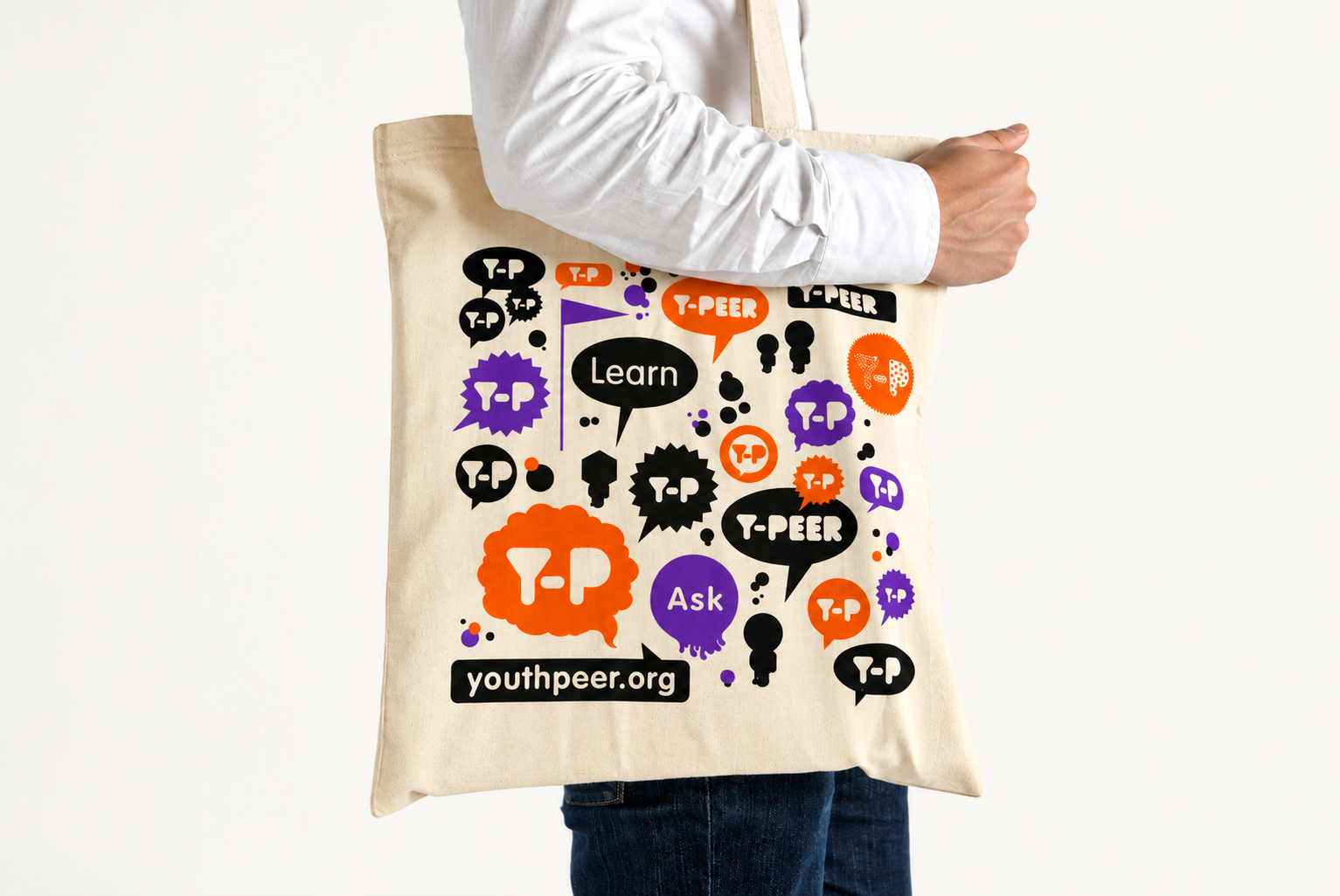 Sac en toile beige avec des graphiques et textes en couleur noir, orange, violet. Le texte inclut des mots comme "Learn", "Ask", "YOUTHPEER.ORG" et des expressions liées au partage et à l'apprentissage comme "T-PEER" et "T-P".