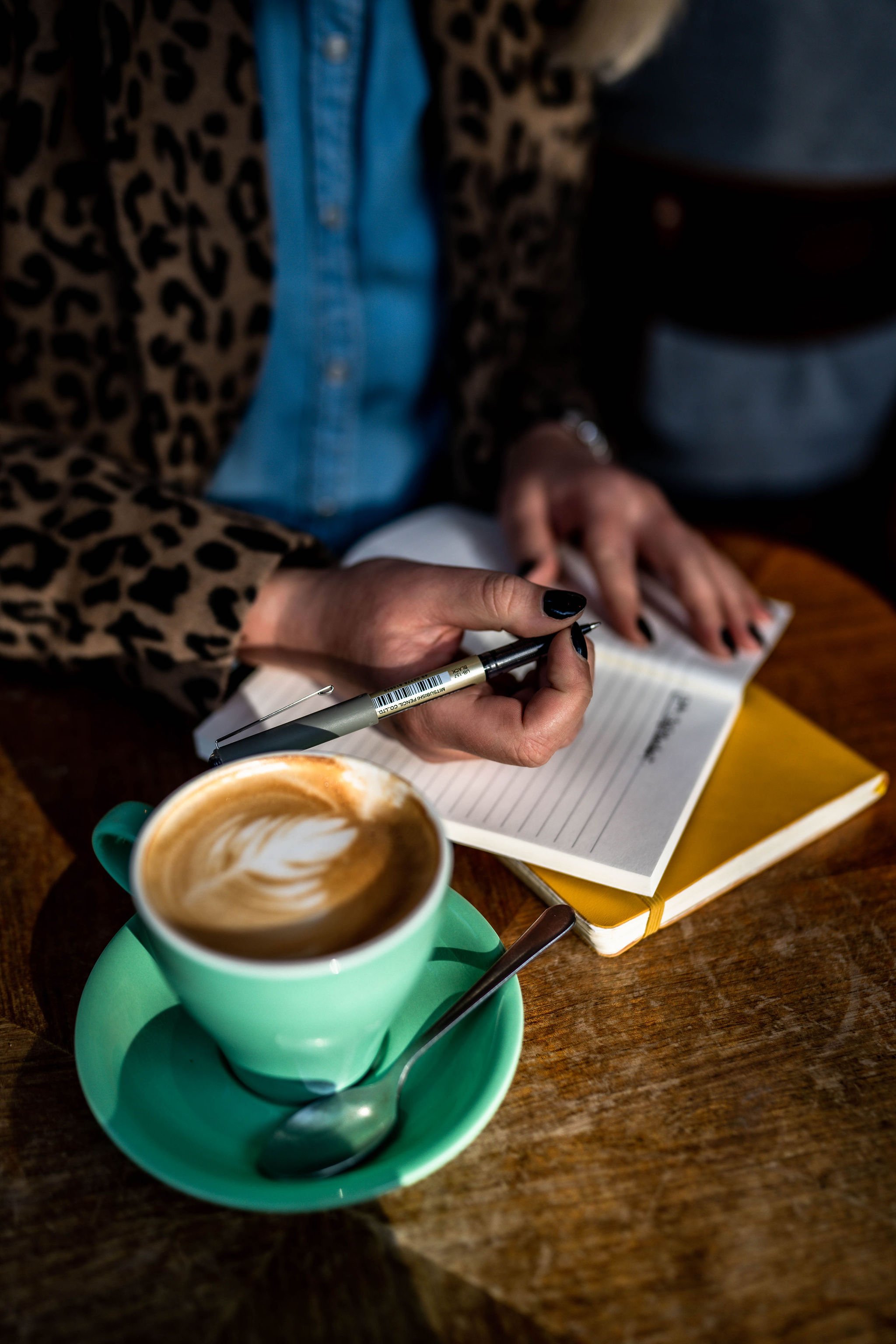 sarah stewart writing in a notebook with a cup of coffee