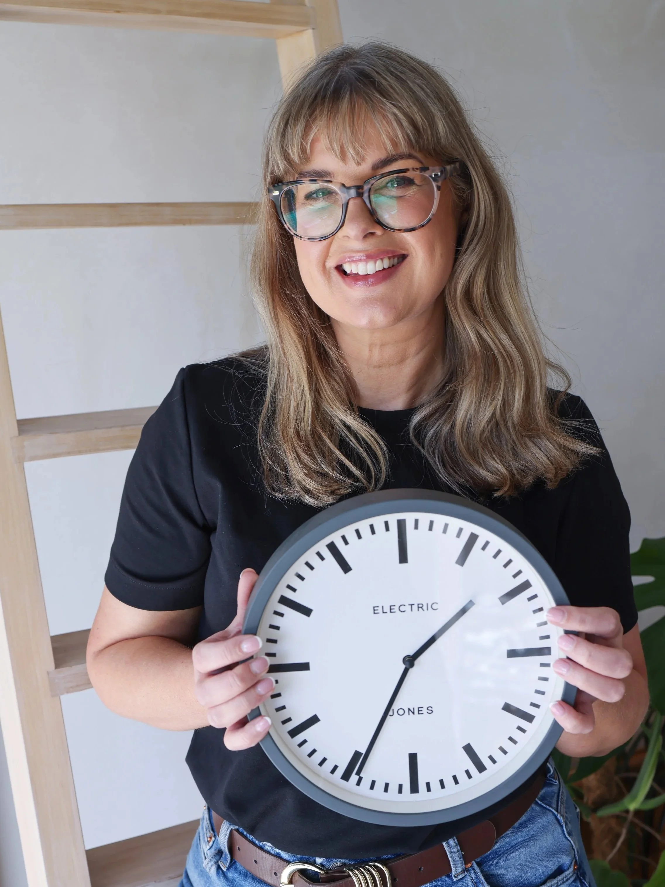 sarah stewart smiling holding a clock