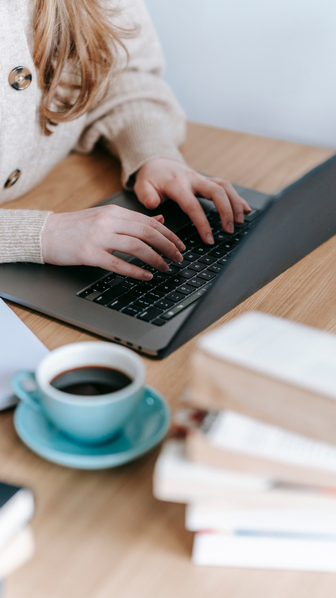 female typing at laptop with coffee by side