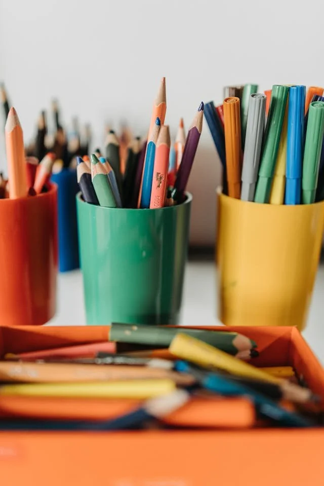Colorful pencils in green, yellow, and red containers on a desk.