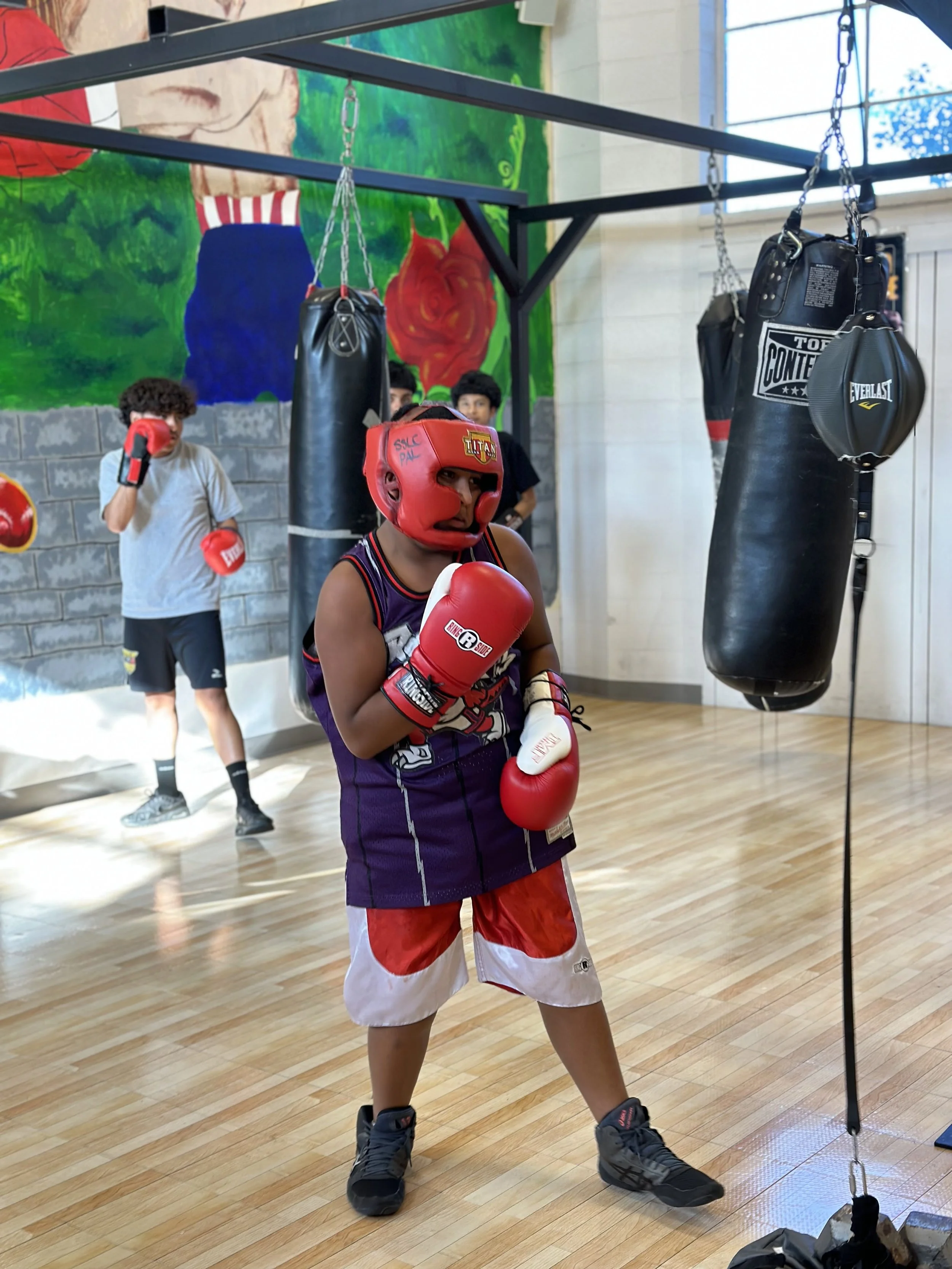 Kid in protective athletic gear practicing boxing.