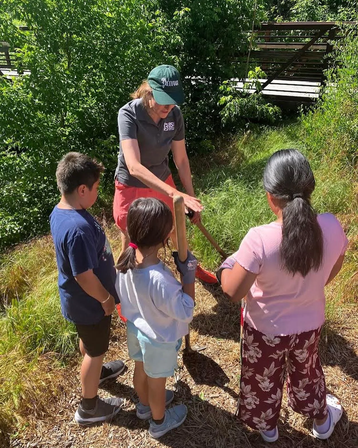 Mentor and kids doing an outdoor landscaping activity.