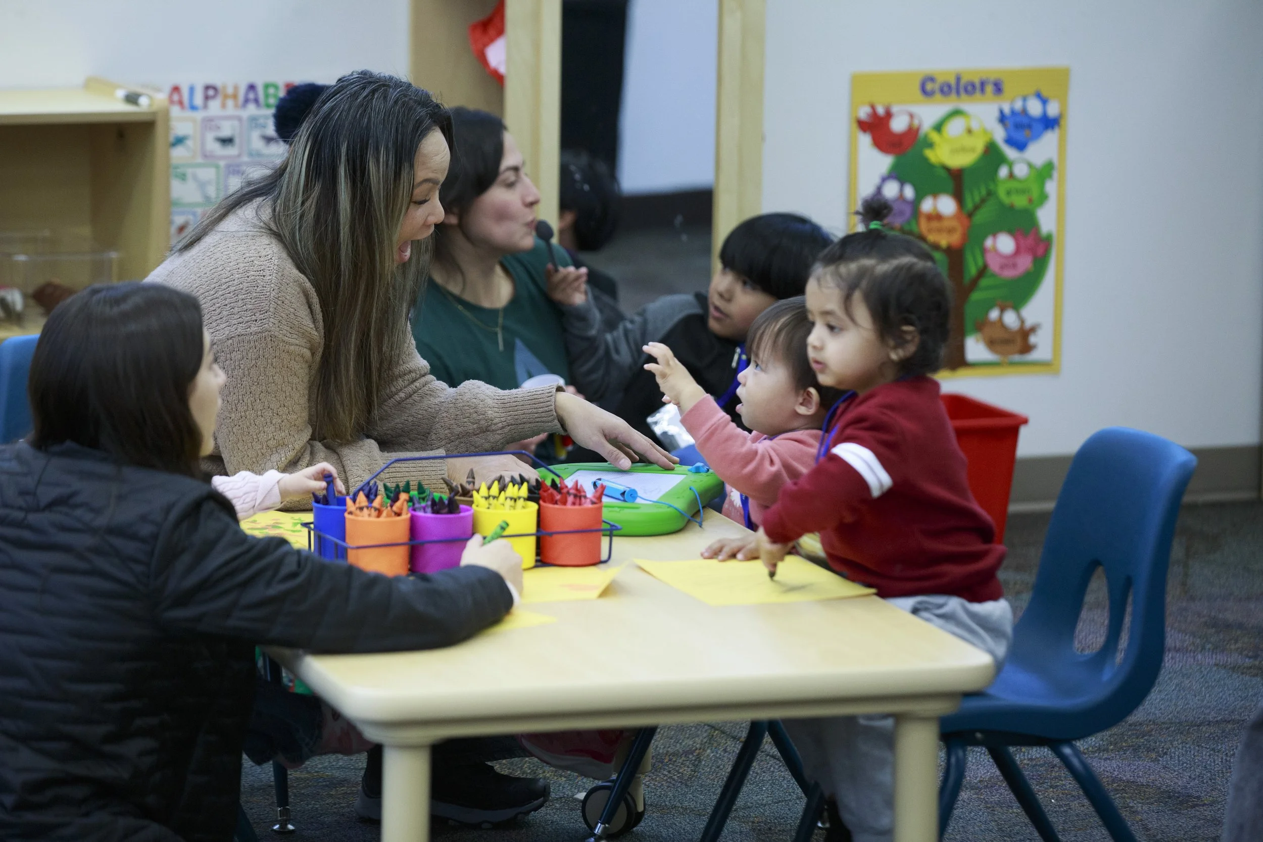 Volunteers providing enrichment activities for babies in a childcare room