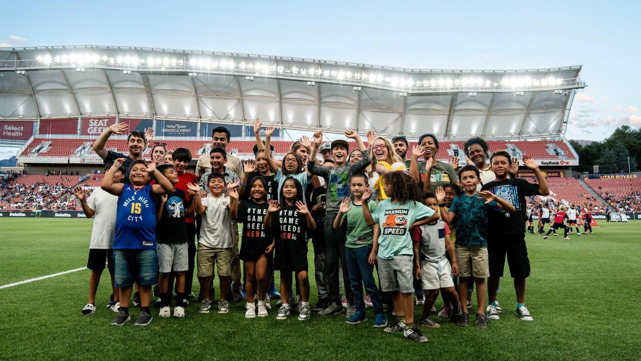 Kids and chaperones cheering in a soccer stadium.