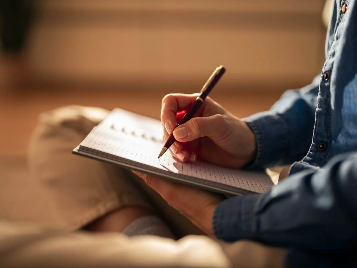 Person writing in a notebook during a reflective exercise related to ERP therapy for OCD.