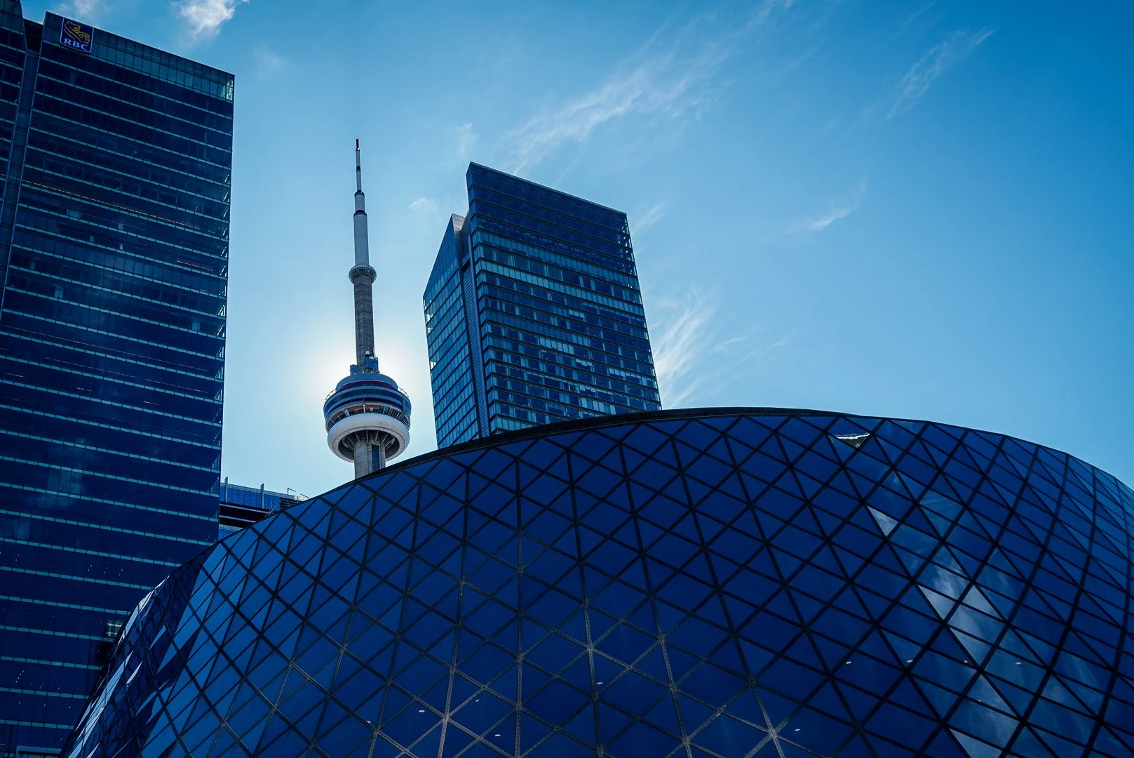 Stadtbild mit modernen Wolkenkratzern in Toronto und CN Tower Fernsehturm bei blauem Himmel.