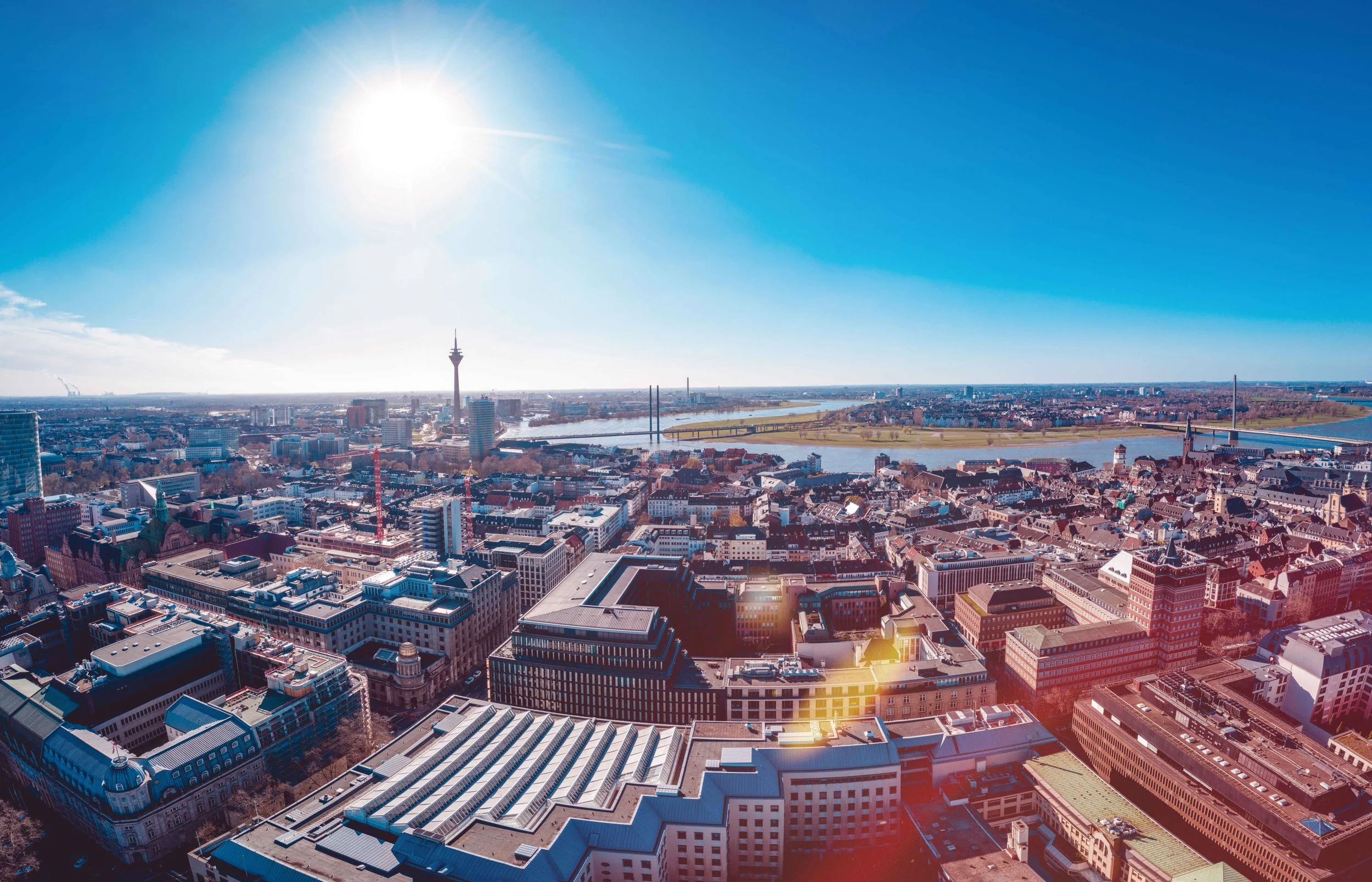 Blick auf Düsseldorf mit Rhein im Hintergrund bei klarem Himmel und Sonne