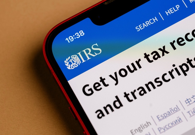 Close-up of a smartphone screen displaying the IRS website with the message 'Get your tax record and transcript'.