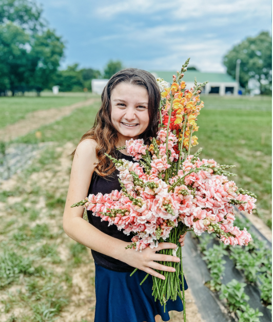 A girl holding a large bouquet of snapdragons flowers at The Flower Meadow You Pick Flower Farm and Barnyard Petting in Coweta, Ok