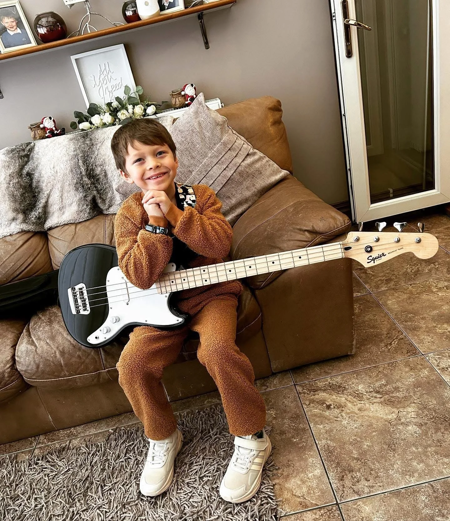 Young guitar student smiles holding a bass guitar after an online music lesson