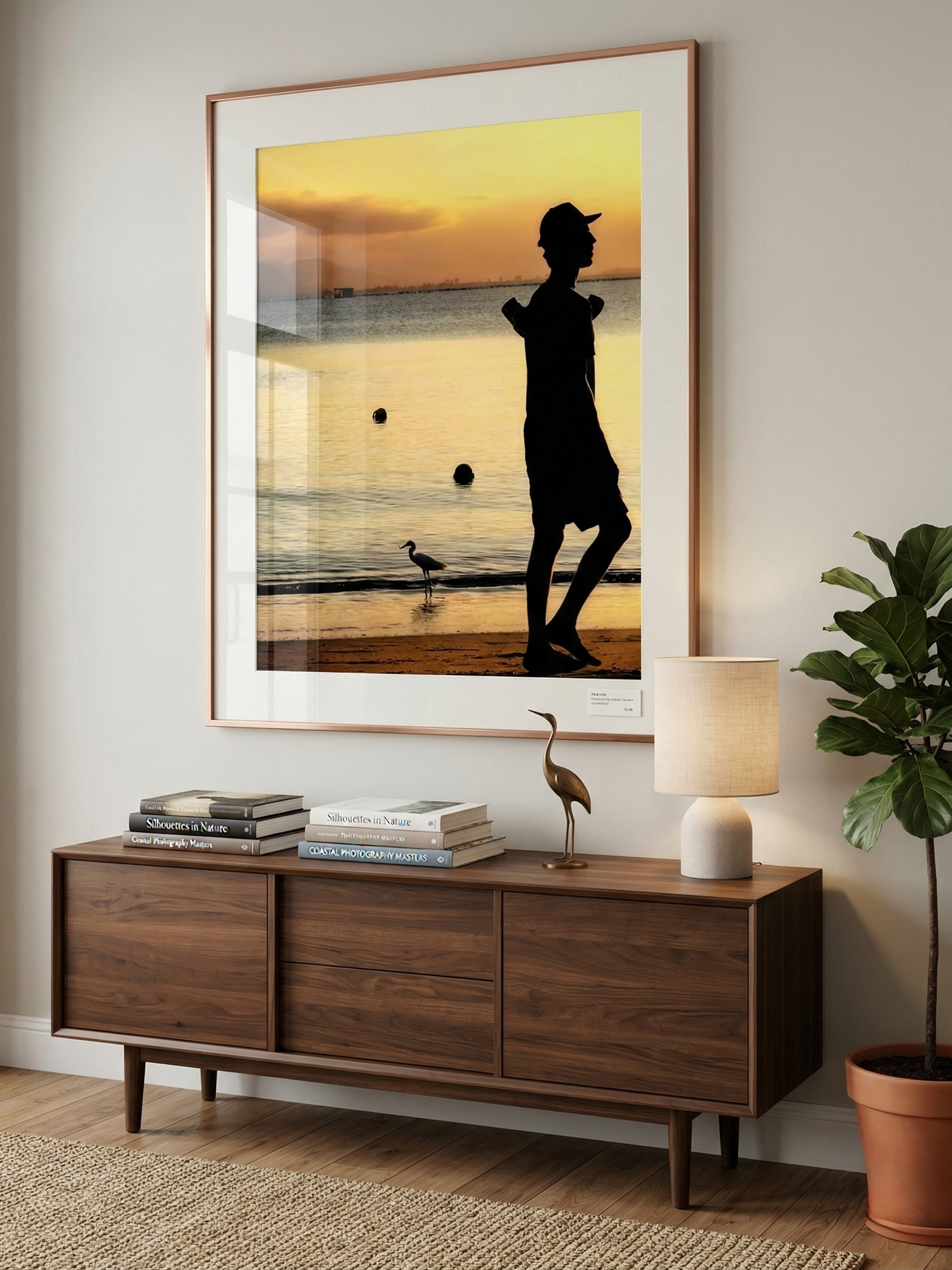 quadro com uma imagem de uma pessoa e um pássaro na praia ao pôr do sol, refletido na parede