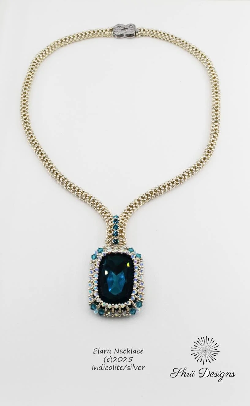 Elegant necklace featuring a large blue gemstone pendant with surrounding smaller stones, displayed on a white background with branding and description.