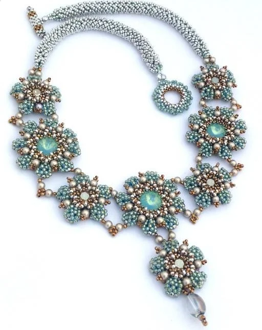 A beaded jewelry set including a necklace, bracelet, and ring, with light blue, silver, and bronze beads arranged in floral patterns.