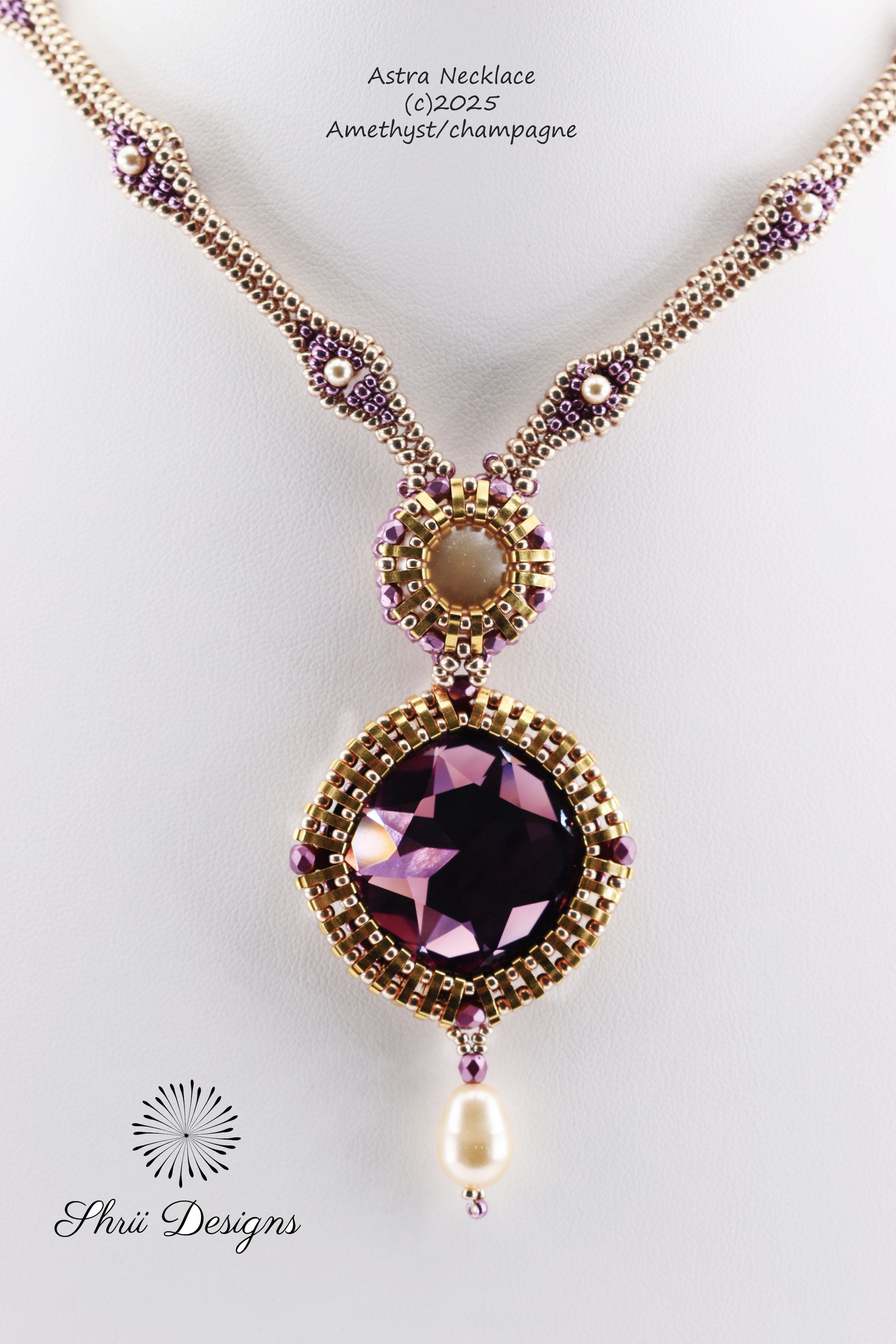 Close-up photo of a necklace with purple gemstones, pearls, and gold accents, featuring a large purple amethyst pendant and a pearl drop, displayed on a white background.