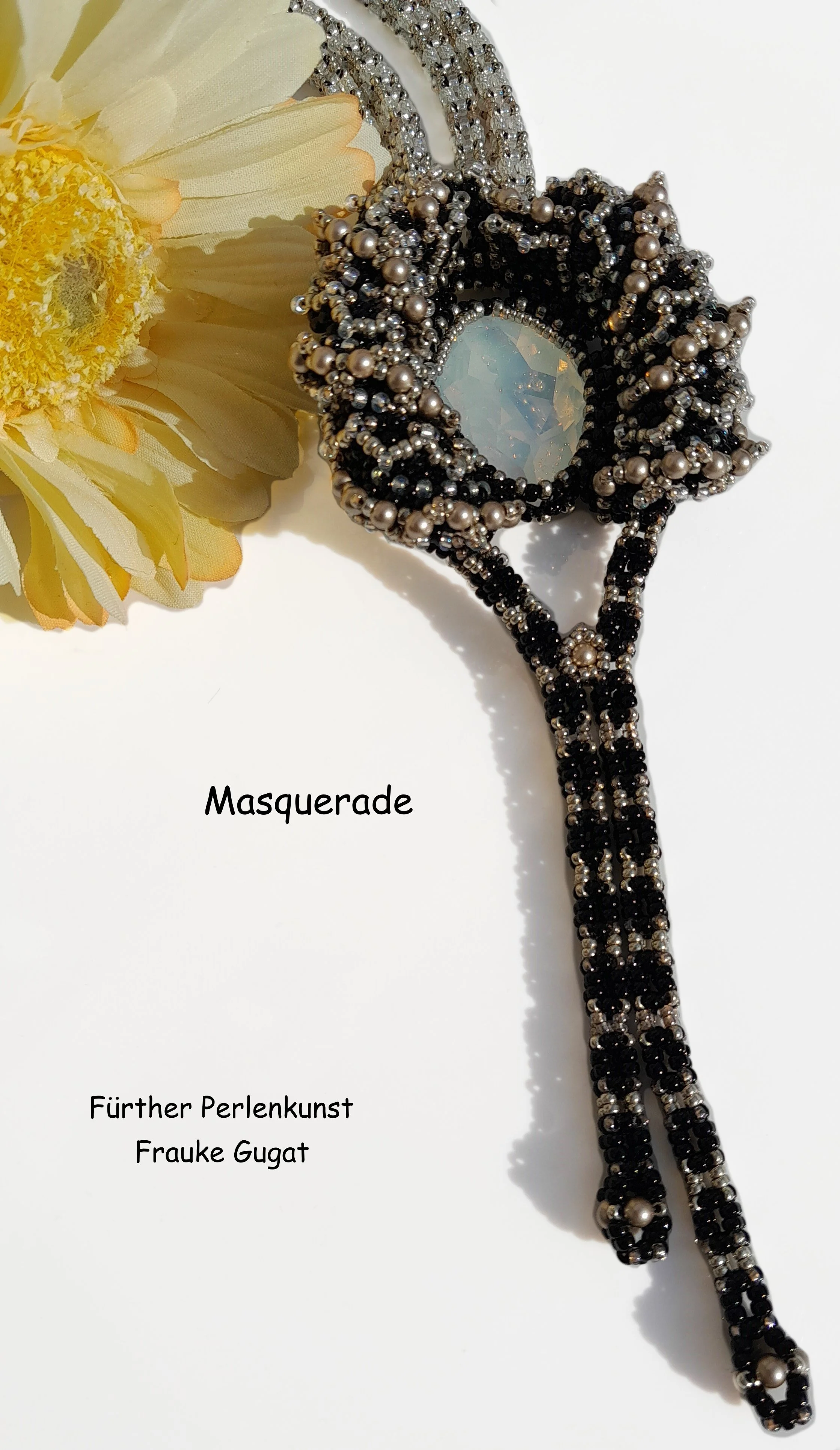 Beaded masquerade mask with black, silver, and pearl beads, partially visible yellow flower, and text 'Masquerade' and 'Fürther Perlkunst Frauke Gugat' on a white background.