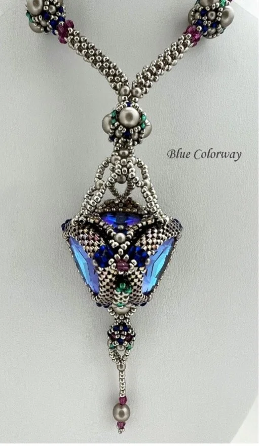 Beaded jewelry necklace with metallic beads, purple, teal, and blue gems, and a large butterfly-shaped pendant with blue gemstones and dangling beads.