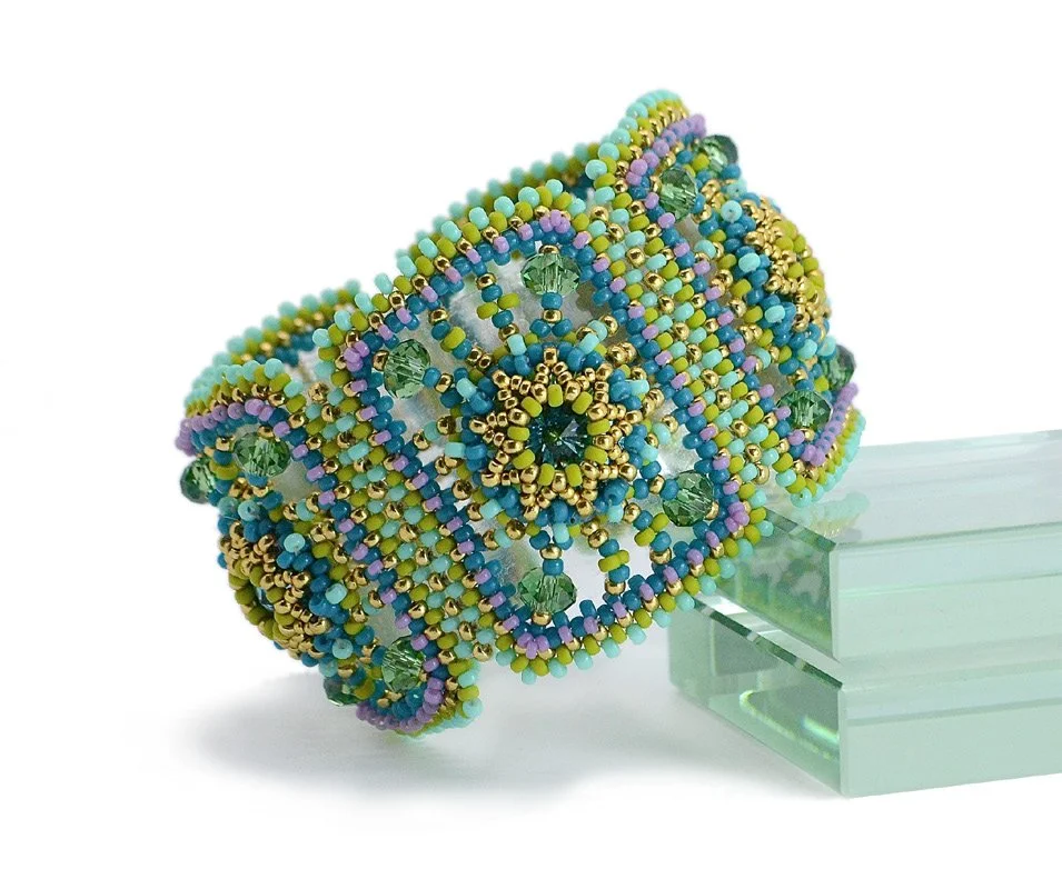 Beaded bracelet with multicolored beads in blue, green, purple, yellow, and gold, arranged in intricate patterns.