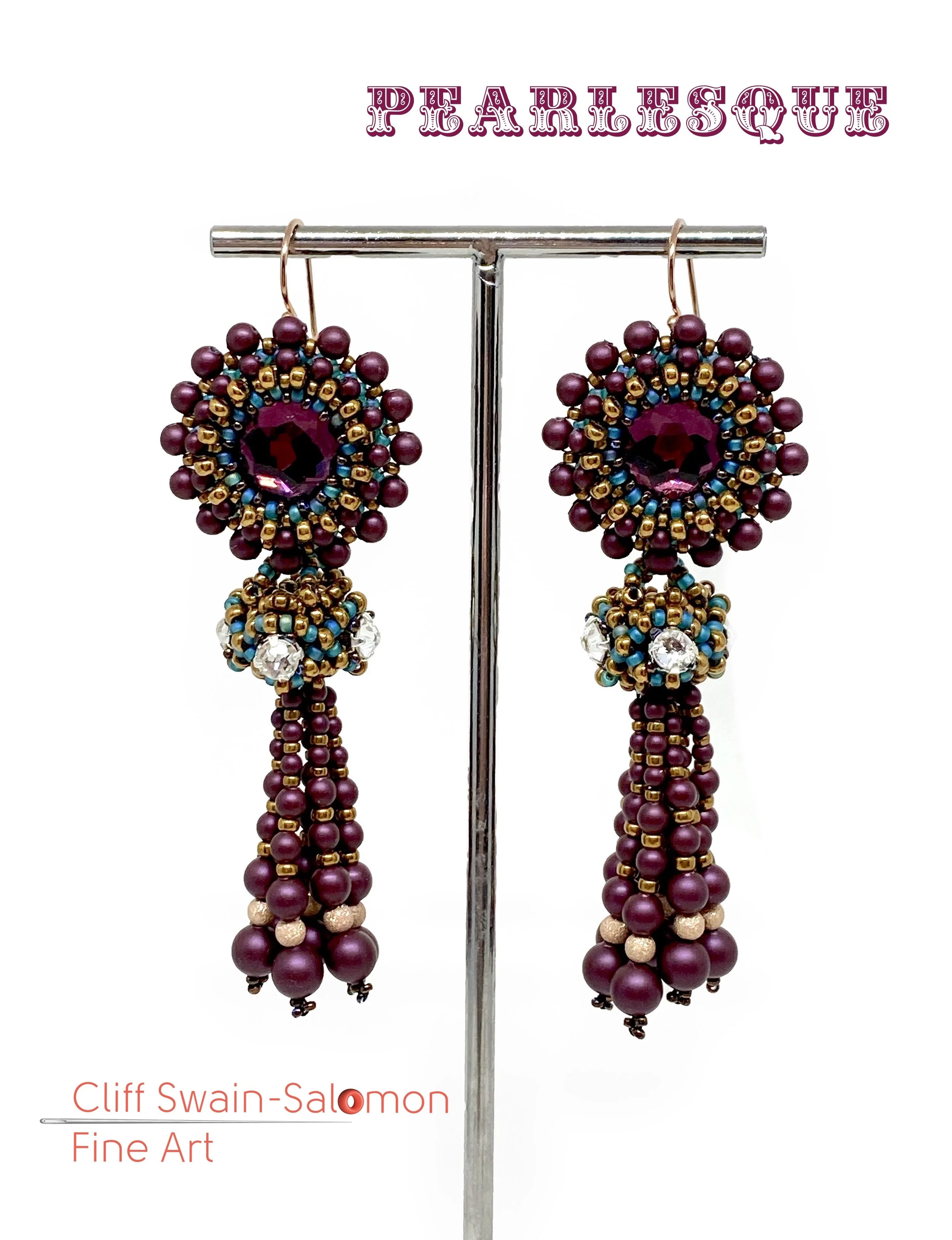 A pair of beaded earrings with maroon, gold, blue, and clear beads hanging on a jewelry display stand. The earrings are circular with a larger central maroon bead and smaller colored beads forming a pattern around it.
