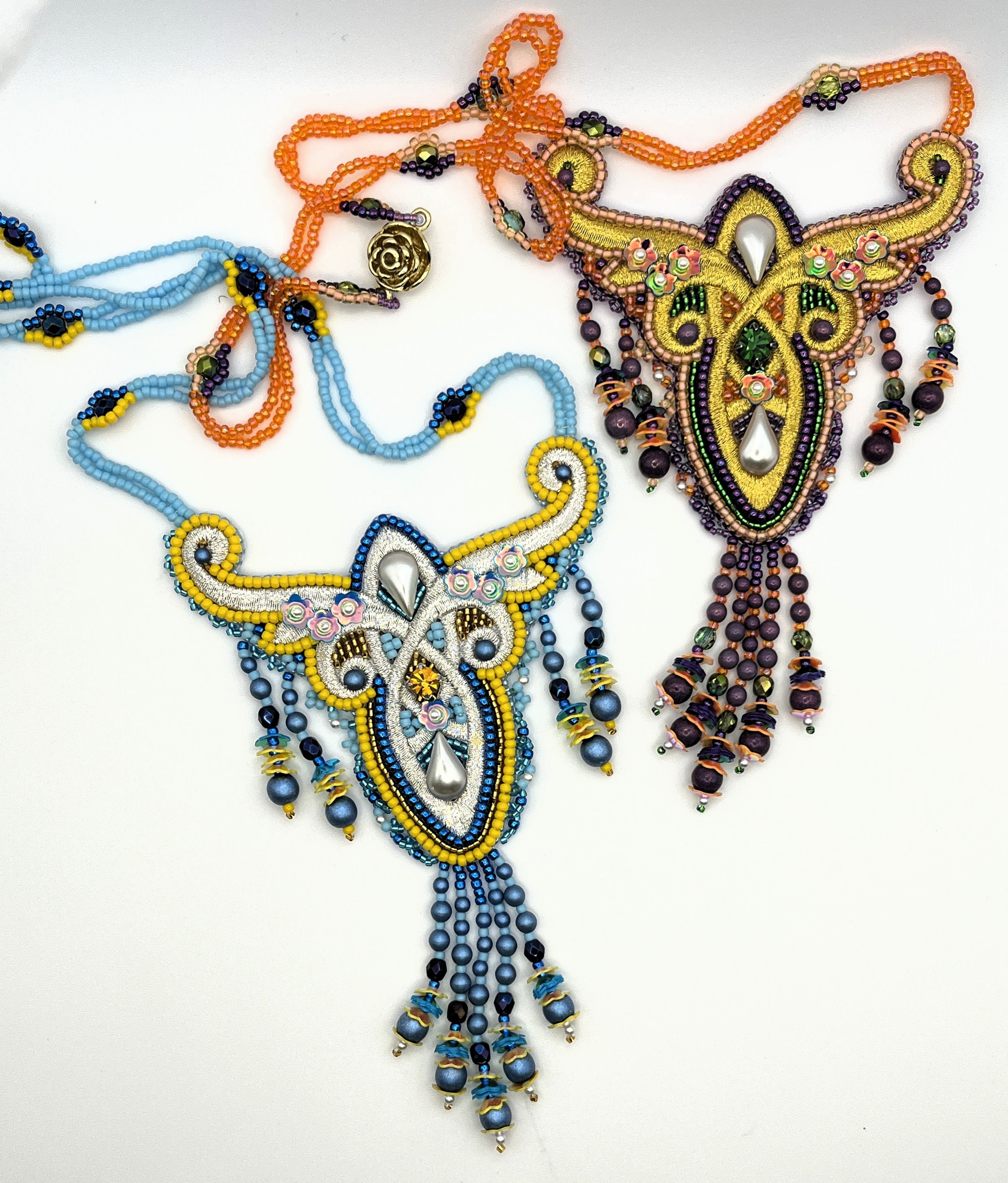 Colorful beaded necklaces and jewelry with butterfly and floral designs on a white background.