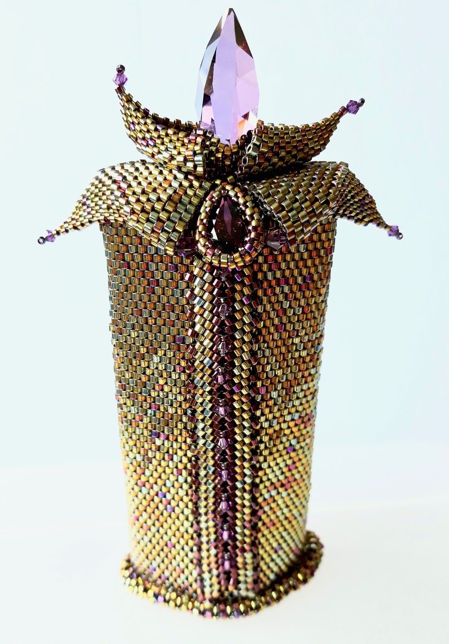 Ornamental container decorated with gold and purple beads, featuring a butterfly-shaped decorative element with purple gemstones and a pink gemstone on top.