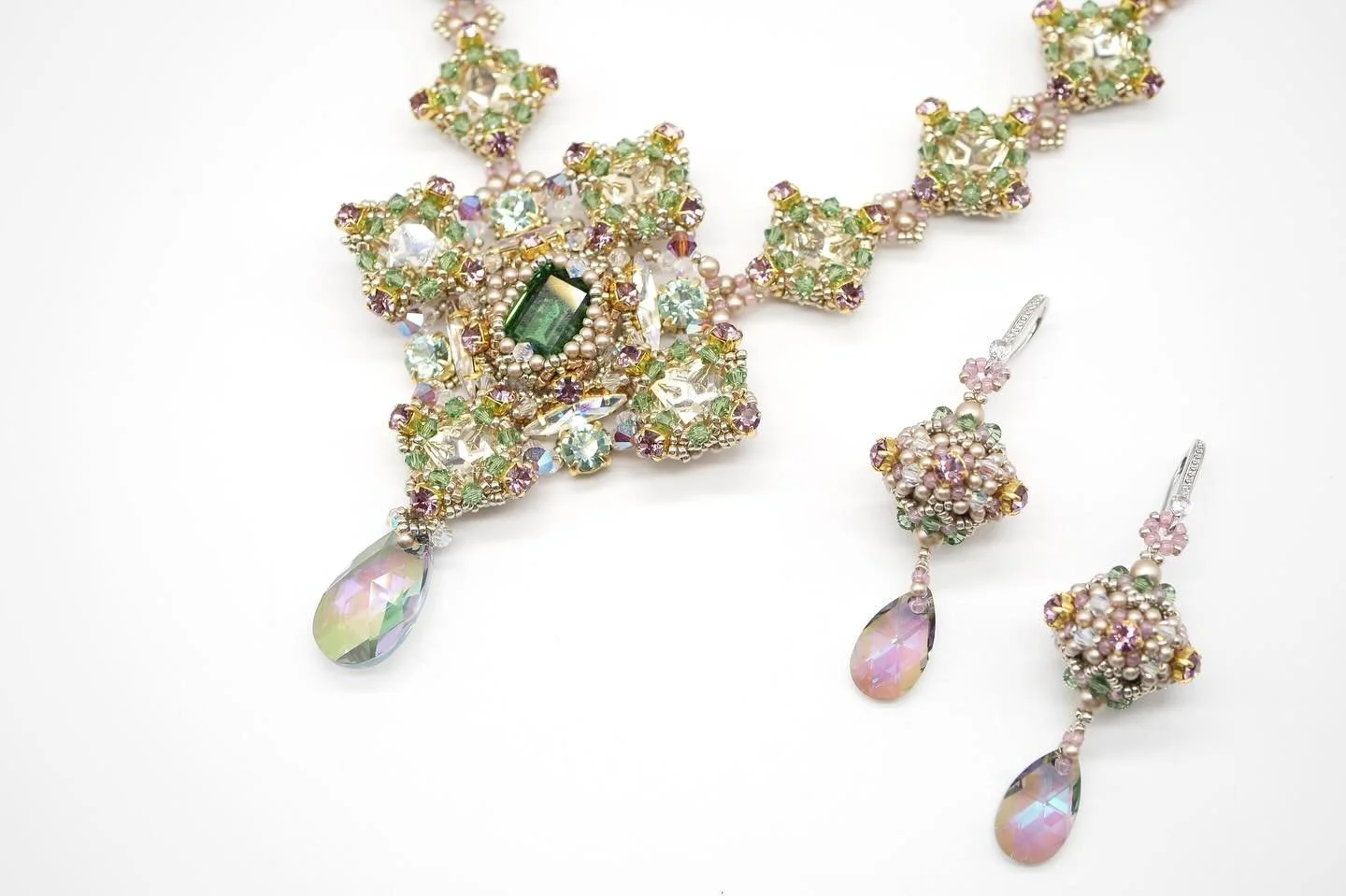 Colorful necklace and earrings with pink, purple, green, and clear crystals, featuring teardrop-shaped pendants.